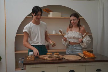 İki genç insan kahvaltı hazırlıyor ve eğleniyorlar. 