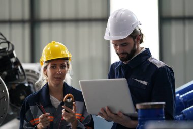 Robot mühendisleri fabrika deposunda robotik kolun bakımı üzerinde çalışıyorlar. İş teknolojisi.