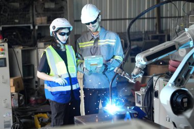 Robot mühendisleri fabrika deposunda robotik kolun bakımı üzerinde çalışıyorlar. İş teknolojisi.