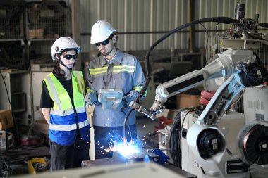Robot mühendisleri fabrika deposunda robotik kolun bakımı üzerinde çalışıyorlar. İş teknolojisi.
