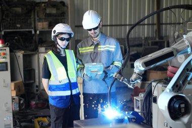 Robot mühendisleri fabrika deposunda robotik kolun bakımı üzerinde çalışıyorlar. İş teknolojisi.