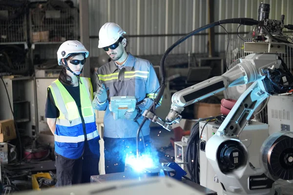 Robot mühendisleri fabrika deposunda robotik kolun bakımı üzerinde çalışıyorlar. İş teknolojisi.