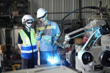 Robot mühendisleri fabrika deposunda robotik kolun bakımı üzerinde çalışıyorlar. İş teknolojisi.