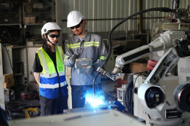 Robot mühendisleri fabrika deposunda robotik kolun bakımı üzerinde çalışıyorlar. İş teknolojisi.