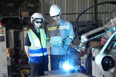 Robot mühendisleri fabrika deposunda robotik kolun bakımı üzerinde çalışıyorlar. İş teknolojisi.