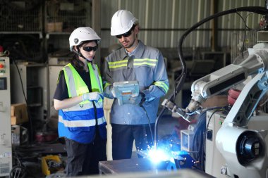 Robot mühendisleri fabrika deposunda robotik kolun bakımı üzerinde çalışıyorlar. İş teknolojisi.