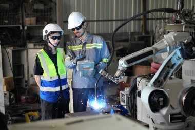 Robot mühendisleri fabrika deposunda robotik kolun bakımı üzerinde çalışıyorlar. İş teknolojisi.