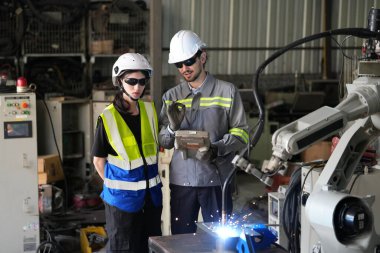 Robot mühendisleri fabrika deposunda robotik kolun bakımı üzerinde çalışıyorlar. İş teknolojisi.