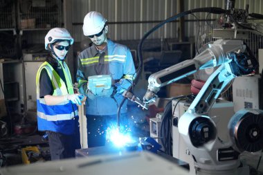 Robot mühendisleri fabrika deposunda robotik kolun bakımı üzerinde çalışıyorlar. İş teknolojisi.