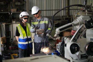 Robot mühendisleri fabrika deposunda robotik kolun bakımı üzerinde çalışıyorlar. İş teknolojisi.