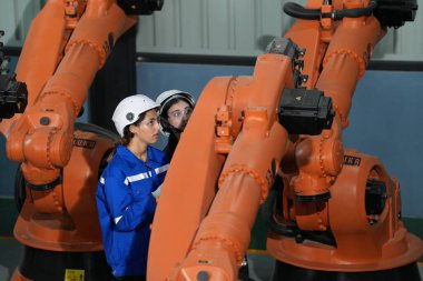 Robot mühendisleri fabrika deposunda robotik kolun bakımı üzerinde çalışıyorlar. İş teknolojisi.