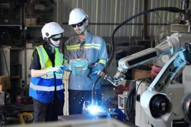 Robot mühendisleri fabrika deposunda robotik kolun bakımı üzerinde çalışıyorlar. İş teknolojisi.