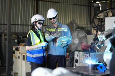 Robot mühendisleri fabrika deposunda robotik kolun bakımı üzerinde çalışıyorlar. İş teknolojisi.