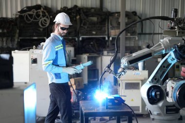 Robot mühendisi fabrika deposunda robotik kolun bakımı üzerinde çalışıyor. İş teknolojisi.