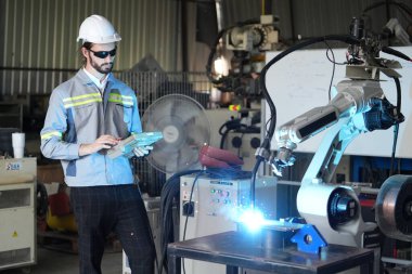 Robot mühendisi fabrika deposunda robotik kolun bakımı üzerinde çalışıyor. İş teknolojisi.