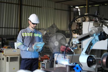 Robot mühendisi fabrika deposunda robotik kolun bakımı üzerinde çalışıyor. İş teknolojisi.