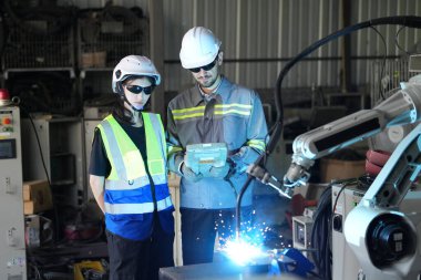 Robot mühendisleri fabrika deposunda robotik kolun bakımı üzerinde çalışıyorlar. İş teknolojisi.