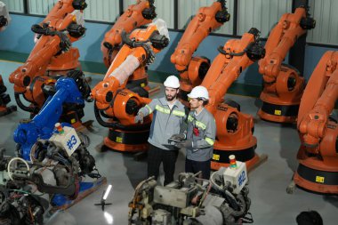 Robot mühendisleri fabrika deposunda robotik kolun bakımı üzerinde çalışıyorlar. İş teknolojisi.