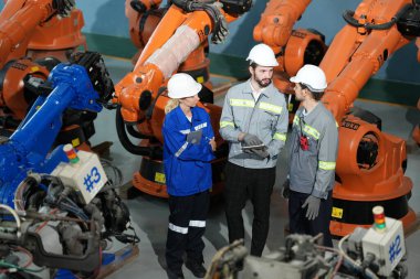 Robot mühendisleri fabrika deposunda robotik kolun bakımı üzerinde çalışıyorlar. İş teknolojisi.