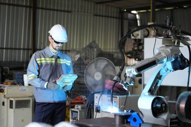 Robot mühendisi fabrika deposunda robotik kolun bakımı üzerinde çalışıyor. İş teknolojisi.