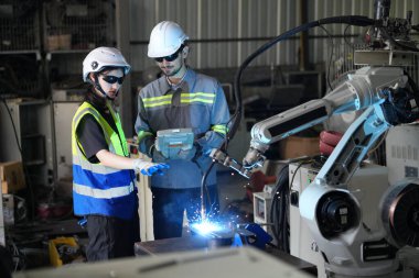 Robot mühendisleri fabrika deposunda robotik kolun bakımı üzerinde çalışıyorlar. İş teknolojisi.