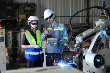 Robot mühendisleri fabrika deposunda robotik kolun bakımı üzerinde çalışıyorlar. İş teknolojisi.