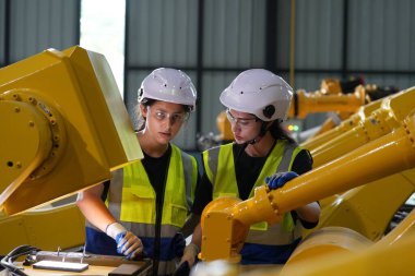 Robot mühendisleri fabrika deposunda robotik kolun bakımı üzerinde çalışıyorlar. İş teknolojisi.