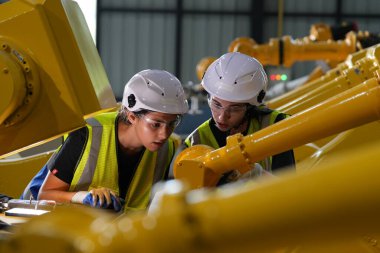 Robot mühendisleri fabrika deposunda robotik kolun bakımı üzerinde çalışıyorlar. İş teknolojisi.