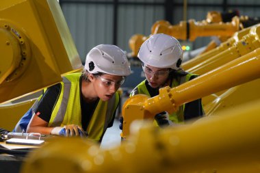 Robot mühendisleri fabrika deposunda robotik kolun bakımı üzerinde çalışıyorlar. İş teknolojisi.