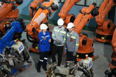 Robot mühendisleri fabrika deposunda robotik kolun bakımı üzerinde çalışıyorlar. İş teknolojisi.