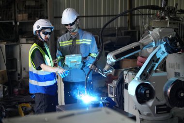 Robot mühendisleri fabrika deposunda robotik kolun bakımı üzerinde çalışıyorlar. İş teknolojisi.