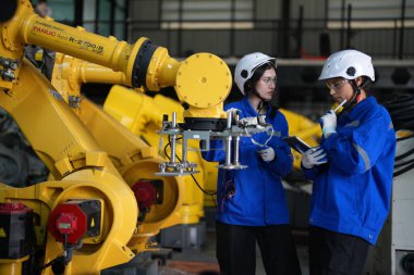 Robot mühendisleri fabrika deposunda robotik kolun bakımı üzerinde çalışıyorlar. İş teknolojisi.