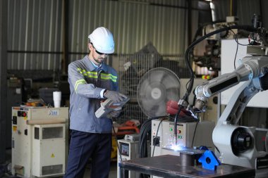 Robot mühendisi fabrika deposunda robotik kolun bakımı üzerinde çalışıyor. İş teknolojisi.
