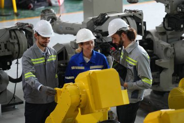 Robot mühendisleri fabrika deposunda robotik kolun bakımı üzerinde çalışıyorlar. İş teknolojisi.