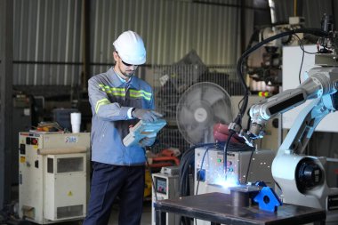 Robot mühendisi fabrika deposunda robotik kolun bakımı üzerinde çalışıyor. İş teknolojisi.
