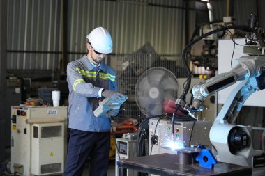 Robot mühendisi fabrika deposunda robotik kolun bakımı üzerinde çalışıyor. İş teknolojisi.