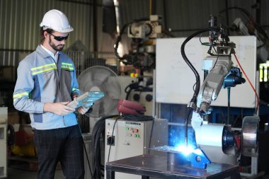 Robot mühendisi fabrika deposunda robotik kolun bakımı üzerinde çalışıyor. İş teknolojisi.