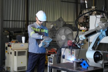 Robot mühendisi fabrika deposunda robotik kolun bakımı üzerinde çalışıyor. İş teknolojisi.