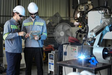 Robot mühendisleri fabrika deposunda robotik kolun bakımı üzerinde çalışıyorlar. İş teknolojisi.