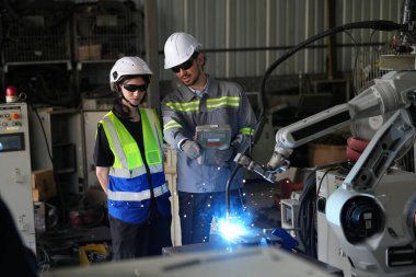 Robot mühendisleri fabrika deposunda robotik kolun bakımı üzerinde çalışıyorlar. İş teknolojisi.