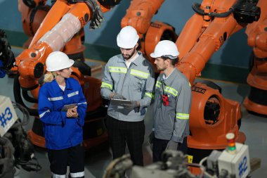 Robot mühendisleri fabrika deposunda robotik kolun bakımı üzerinde çalışıyorlar. İş teknolojisi.