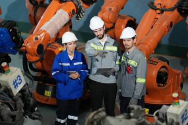 Robot mühendisleri fabrika deposunda robotik kolun bakımı üzerinde çalışıyorlar. İş teknolojisi.