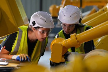 Robot mühendisleri fabrika deposunda robotik kolun bakımı üzerinde çalışıyorlar. İş teknolojisi.