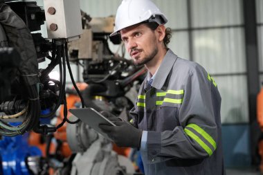 Robot mühendisi fabrika deposunda robotik kolun bakımı üzerinde çalışıyor. İş teknolojisi.