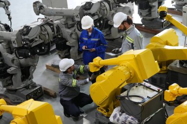 Robot mühendisleri fabrika deposunda robotik kolun bakımı üzerinde çalışıyorlar. İş teknolojisi.