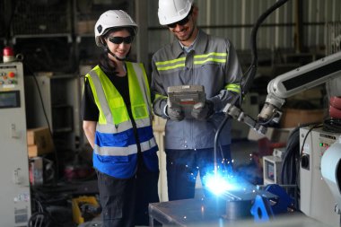 Robot mühendisleri fabrika deposunda robotik kolun bakımı üzerinde çalışıyorlar. İş teknolojisi.