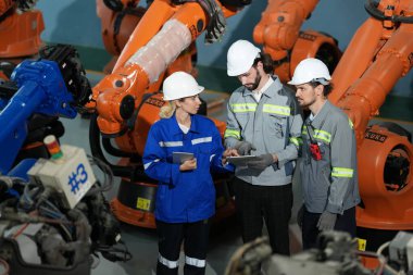 Robot mühendisleri fabrika deposunda robotik kolun bakımı üzerinde çalışıyorlar. İş teknolojisi.