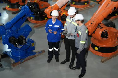 Robot mühendisleri fabrika deposunda robotik kolun bakımı üzerinde çalışıyorlar. İş teknolojisi.