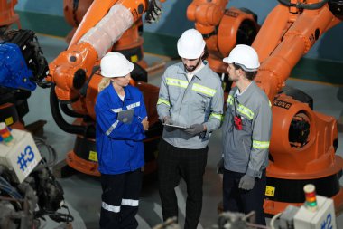 Robot mühendisleri fabrika deposunda robotik kolun bakımı üzerinde çalışıyorlar. İş teknolojisi.