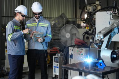 Robot mühendisleri fabrika deposunda robotik kolun bakımı üzerinde çalışıyorlar. İş teknolojisi.